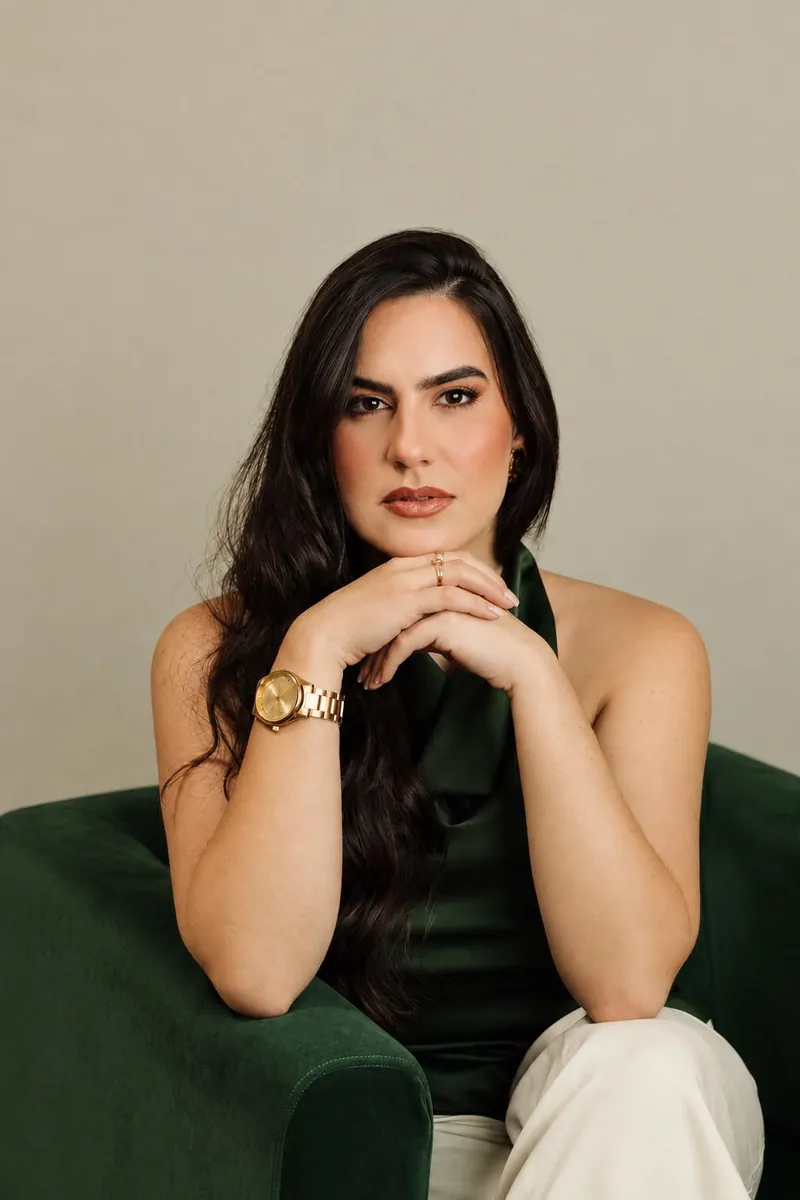 Retrato de Raissa Macedo com blusa verde, mãos apoiadas no queixo